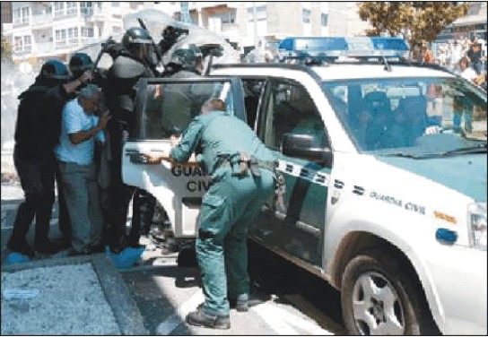Avelino Fernández, portavoz del PINN, entra en un coche de la Guardia Civil protegido por antidisturbios. / j. lores / FARO DE VIGO